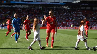 Fussballspielerin gibt Mädchen auf dem Spielfeld High Five.",