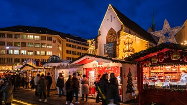 Basler Weihnachtsmarkt bei Nacht mit erleuchteten Ständen und Menschenmenge.