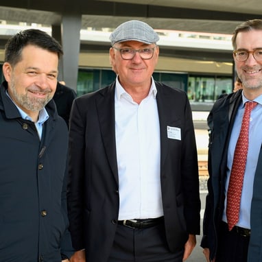 Drei Männer in Anzügen stehen zusammen für ein Foto.",