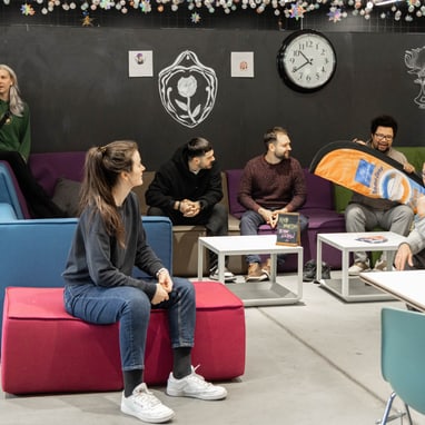 Gruppe von Menschen im Freizeitraum mit Sofas und Tischtennisbrett.