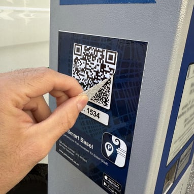 Hand scannt QR-Code an Parkuhr.