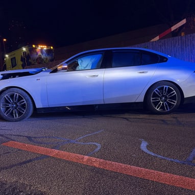 Weisses Auto mit Frontschaden bei Nacht auf Strasse geparkt.