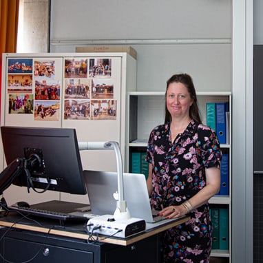 FMS-Lehrerin Kathrin Urscheler steht an einem Schreibtisch mit Computer in einem Klassenzimmer..
