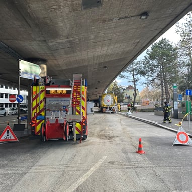 Ölspurbeseitigung unter Brücke mit Einsatzfahrzeugen und Absperrung.",