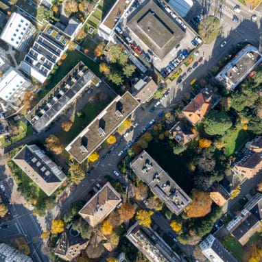 Luftaufnahme von Gebäuden und Strassen mit Bäumen im Herbst.
