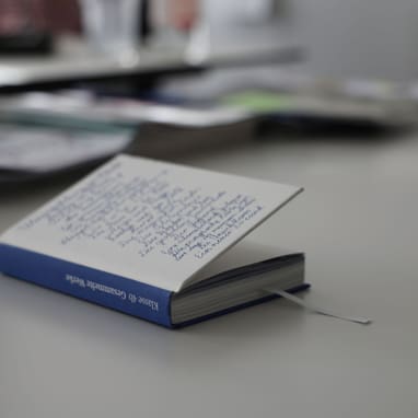 Aufgeschlagenes Buch auf Tisch mit Hintergrund unscharf.