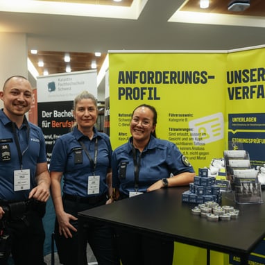 Die Resortleitung und eine Mitarbeiterin der Rekrutierung stehen an einem Infostand.