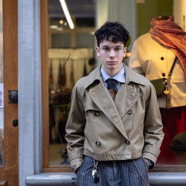 Person vor einem Schaufenster mit Kleidung und Dekorationen im Hintergrund.