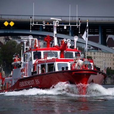 Feuerlöschboot auf dem Fluss vor Brücke in Basel.",