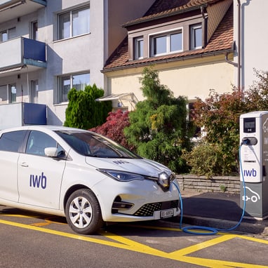 Elektroauto lädt an Ladestation vor Wohngebäude.