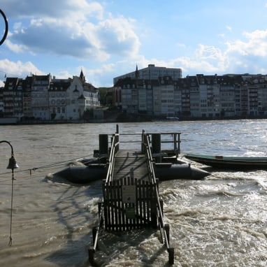 Überschwemmtes Ufer der Stadt mit Strassenlaterne und Teil einer Brücke.