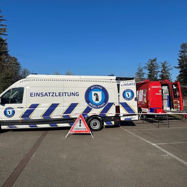 Notfallfahrzeuge auf einem Parkplatz bei Tageslicht.",