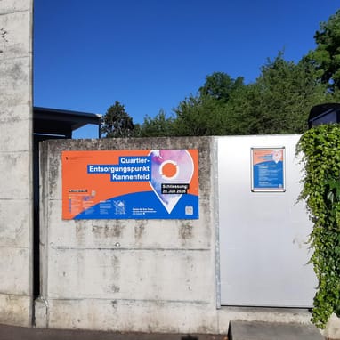 Betonwand mit buntem Plakat und grünem Laub.