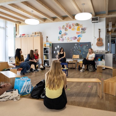 Gruppe von Menschen, die in einem Kinderzimmer im Kreis sitzen.