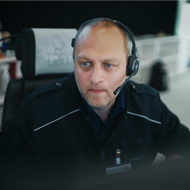 Mann mit Headset sitzt konzentriert vor einem Bildschirm in der Rettungszentrale.