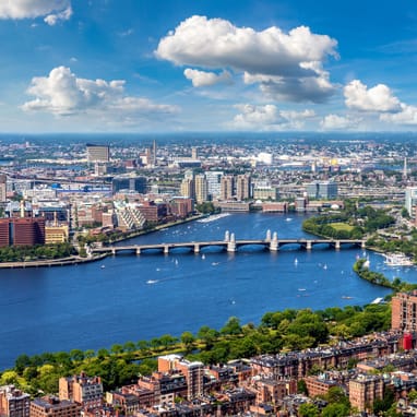 Stadtansicht mit Fluss und Brücke unter blauem Himmel.