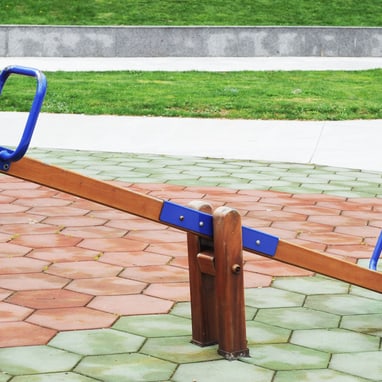 Wippe auf Spielplatz mit gepflastertem Boden.