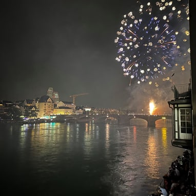 Feuerwerk über der Stadt bei Nacht mit Fluss im Vordergrund.