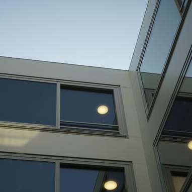 Blick nach oben auf modernes Gebäude mit Glasfenstern.