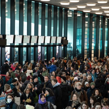 Menschenmenge in modernem Gebäude mit grosser Fensterfront.