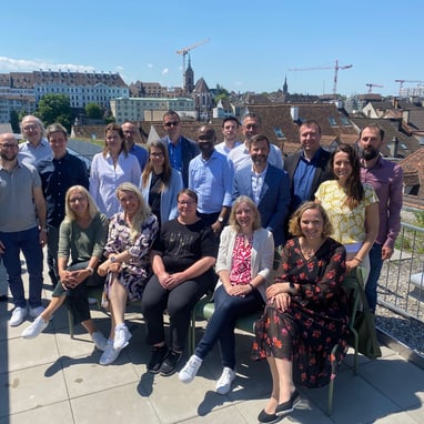 Gruppe von Menschen auf einer Dachterrasse mit Stadtblick im Hintergrund.