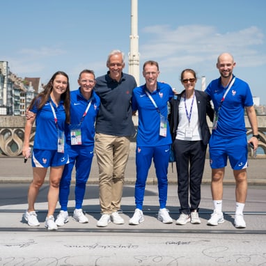 Gruppe von Menschen in Sportkleidung auf Brücke bei Sonnenschein.