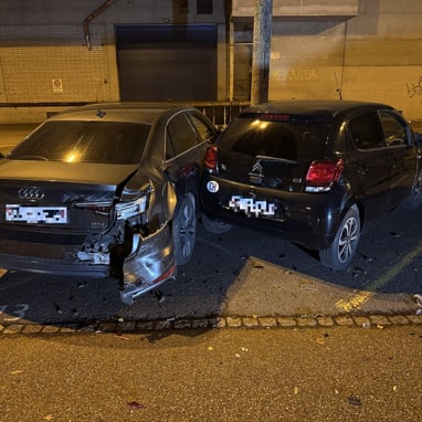 Zwei beschädigte Autos auf einem Parkplatz bei Nacht.",