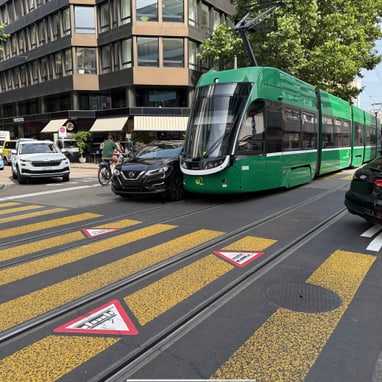 Grüne Strassenbahn kollidiert mit Auto auf städtischer Kreuzung.