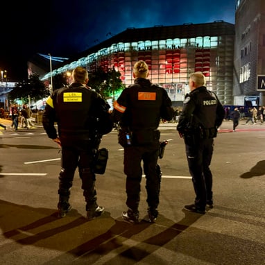 Polizisten auf der Strasse bei Nacht vor Gebäude mit rotem Licht.