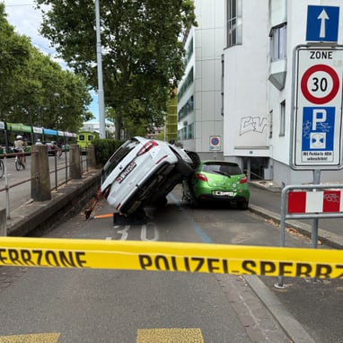 Ein Auto ist auf seiner Seite gekippt und ein anderes Auto steht daneben, mit einem Polizeiband im Vordergrund.