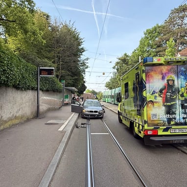 Auto blockiert Strassenbahngeleise neben Rettungsfahrzeug.