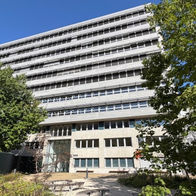 Mehrstöckiges Gebäude mit Bäumen im Vordergrund.