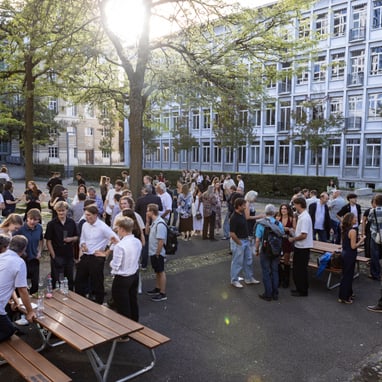 Menschenmenge auf einem Schulhof bei Sonnenschein.