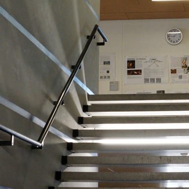 Moderne Treppe mit Wanduhren und Plakaten.