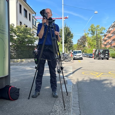 Fotograf mit Stativ auf städtischer Strasse.