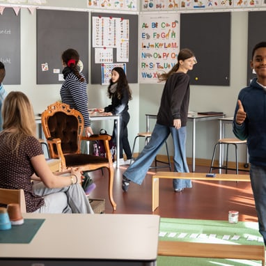 Kinder und Lehrerin in einem belebten Klassenzimmer.