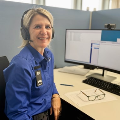 Frau mit Headset sitzt an Schreibtisch mit zwei Monitoren.