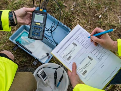 Personen analysieren Daten im Freien mit einem Messgerät und Formular.