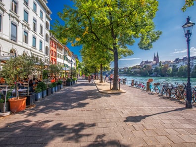 Flussuferpromenade mit Bäumen und Fahrrädern, sonniger Tag.