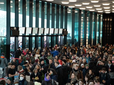 Menschenmenge in modernem Gebäude mit grosser Fensterfront.