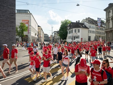 Menschenmenge in roter Kleidung bei einer Strassenparade in der Stadt.