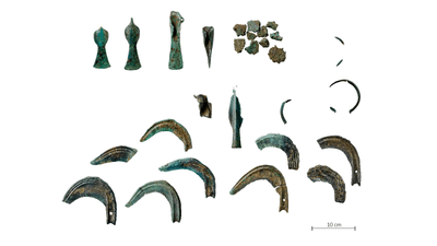 Verschiedene antike Metallfragmente aus Bronze auf weissem Hintergrund mit Massstab 10cm