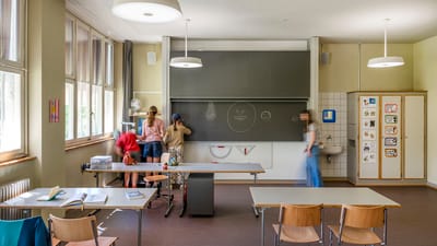 Klassenzimmer mit mehreren Personen, die an der Tafel stehen.
