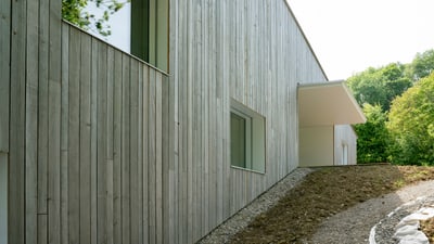 Modernes Gebäude mit Holzverkleidung und Waldblick.