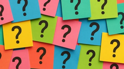 Bunte Karten mit Fragezeichen übereinandergelegt.