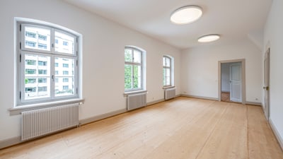 Leerer Raum mit Holzboden und Fenstern.