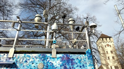 Mehrere meteorologische Geräte auf einem bunten Gebäude vor einem Turm.