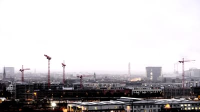 Stadtlandschaft bei Nebel mit Baukränen.