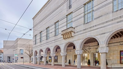 Aussenansicht eines historischen Gebäudes mit Arkaden und Strassenbahnlinien. Die warmtonige neoklassizistische Architektur wurde vom Basler Architekten Rudolf Christ und dem Stuttgarter Baumeister Paul Bonatz zusammen entworfen.