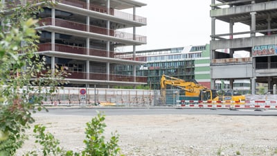 Baustelle mit unfertigen Gebäuden und Ausgrabungsmaschine.